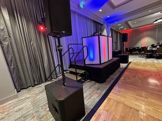 Galaxy DJ booth with line-array sound and blue and red color uplighting set up in a hotel ballroom
