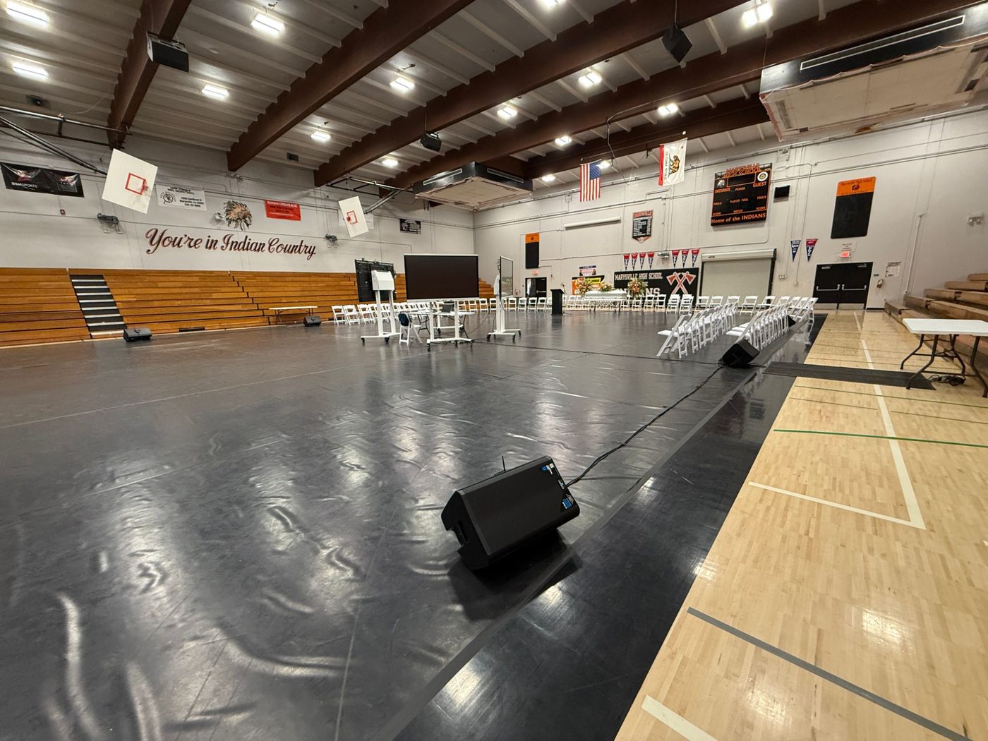 Live sound speakers and podium set up in a high school gymnasium for a ceremony